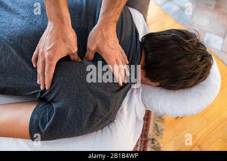 Thérapeute massant de nouveau à un sportif fort. Un patient masculin recevant le traitement de massages thérapeutiques sportifs dans la clinique médicale Banque D'Images