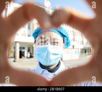 Une travailleuse médicale chinoise masquée fait un cœur avec ses mains lorsqu'elle retourne avec d'autres collègues à ses propres postes après 14 jours d'isolement et d'observation médicale après avoir travaillé dans le service d'isolement pour les patients infectés par le nouveau coronavirus et la pneumonie à l'hôpital No.4 Dans la ville de Huai'an, dans la province de Jiangsu en Chine orientale, le 22 février 2020. (Photo de Zhao Qirui / Costfoto/Sipa USA) Banque D'Images