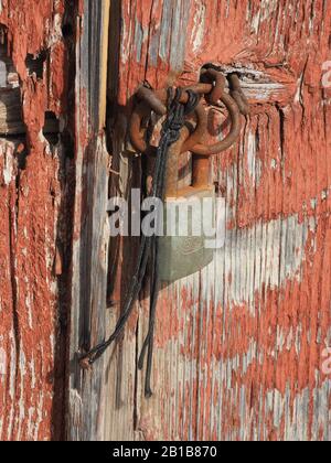 Ancienne porte en bois avec peinture écaillée et attachée avec une serrure rouillée et une longueur de ficelle à Kythira, Grèce. Banque D'Images