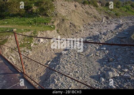 Une ancienne rivière rouillée étroite croisant . Sale, rivière pierreuse . un pont suspendu encore fait d'un support en fer a été utilisé pour traverser la rivière reliant le Banque D'Images