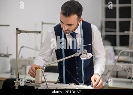 Homme sur mesure debout lors de la vérification de la machine à coudre Banque D'Images