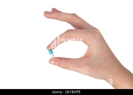 Main de la jeune femme offrant une capsule bleue et blanche isolée sur fond blanc Banque D'Images