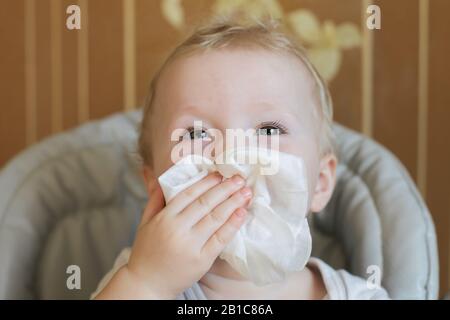 l'enfant balaye son nez avec un mouchoir blanc. Symptôme de coronavirus Banque D'Images