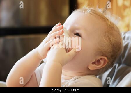 l'enfant balaye son nez avec un mouchoir blanc. Enfant avec rhinite froide. Virus et infection. Symptôme de coronavirus. Vue latérale Banque D'Images