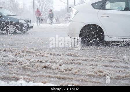 Trafic urbain dans la tempête de neige, flou de mouvement. Les voitures traversent une route désordonnée non nettoyée, concept de sécurité routière dans les mauvaises conditions météorologiques Banque D'Images