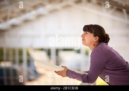 Une femme adulte de taille moyenne qui a l'air réfléchie tout en tenant un imprimé bleu. Banque D'Images
