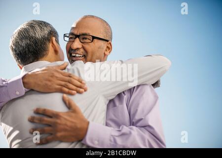 Les hommes d'affaires se saluant les uns les autres avec un hug. Banque D'Images