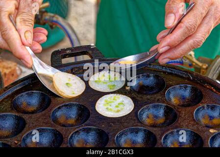 L'alimentation de rue traditionnelle thaïlandaise, dessert Kanom Krok ou crêpes de riz à la noix de coco. A l'arrière-plan de l'alimentation de rue à partir de la Thaïlande Banque D'Images