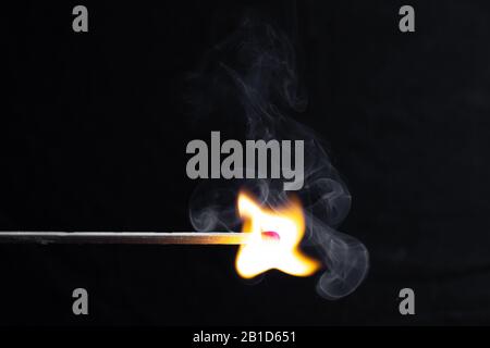un match brûlant avec une flamme vive sur un fond noir Banque D'Images