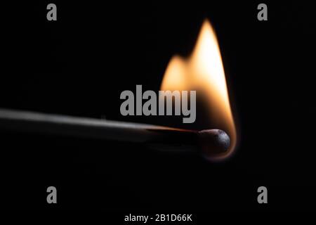un match brûlant avec une flamme vive sur un fond noir Banque D'Images