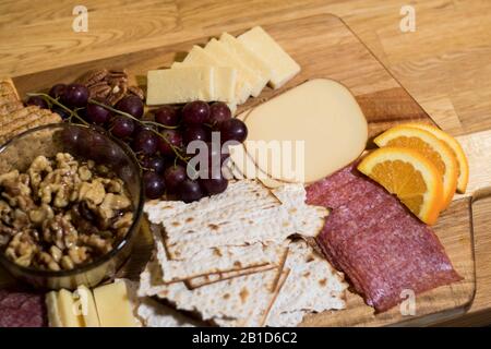 Table de charcuterie près de la table de charcuterie froide avec des doigts sur plateau en bois. Fromage gastronomique en tranches et viande servis sur une planche de charcuterie en bois. Banque D'Images