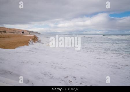 L'océan de tempête et la silhouette de pêcheurs sur la plage. Scène tranquille, jour couvert, beau ciel nuageux fond Banque D'Images