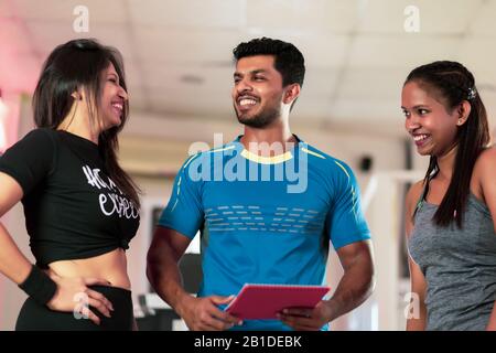 Entraîneur personnel beau parler avec son client à la salle de sport Banque D'Images