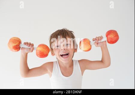 joyeux enfant actif fort et plein de rire dans le réservoir de levage des haltères faits de fruits de pomme Banque D'Images