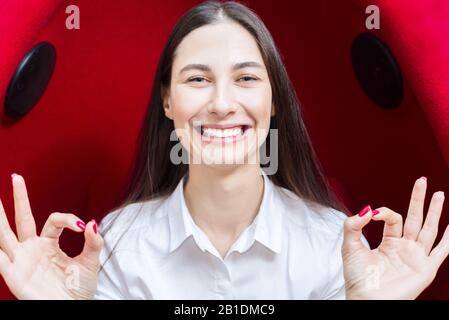 bonne jeune fille souriante. femme montre le geste tout est bien. fond rouge Banque D'Images