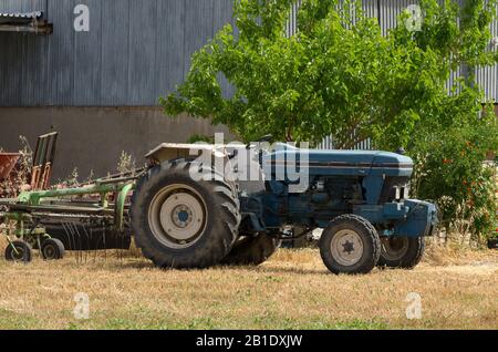 Tracteur bleu gros plan sur un champ fauté le jour ensoleillé sur l'arrière-plan du bâtiment (Rhodes, Grèce) Banque D'Images