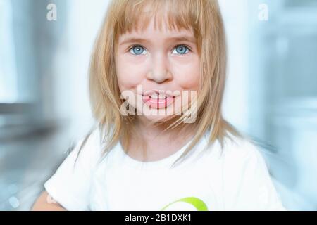 Portrait de charmante petite fille aux yeux bleus et cheveux blond. Un enfant de charme est souriant et heureux. Gros plan extrême. Banque D'Images