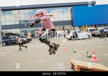 Kiev/Ukraine - 09.22.2019: Compétition de rue à rouliers entre enfants. En ligne skater petite fille est le saut virtuoso. La vie sportive de ville. Banque D'Images