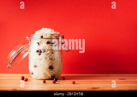 Chou fermenté avec canneberge dans un pot en verre sur fond de bois et de rouge. Probiotiques concept alimentaire. Régime végétarien préservé, fermentation maison. Bannière avec espace de copie. Banque D'Images