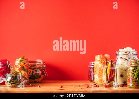 Assortiment de divers aliments fermentés et marinés sur fond en bois, espace de copie. Légumes fermentés, sauerkraut, poivre, ail, betterave, carotte coréenne, kimchi de concombre en pots de verre Banque D'Images