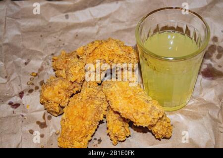 Ailes de poulet panées et un verre de limonade sur fond de papier gris. Gros plan Banque D'Images