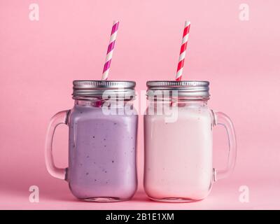 Smoothie aux fraises et aux bleuets en verre maçon sur fond rose. Banque D'Images