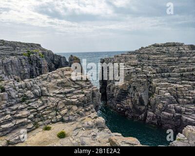 Vue imprenable sur les falaises de l'île San Pietro, d'énormes strates rocheuses grises s'élèvent au-dessus de la mer avec de l'eau émeraude, destination naturelle de voyage avec ma Banque D'Images