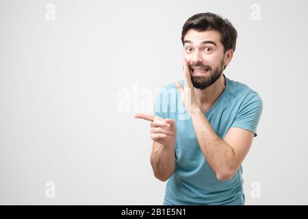 Homme barbu hispanique chuchotant des potins isolés sur un fond blanc Banque D'Images