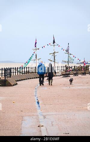 Un couple d'âge moyen prend son chien pour une promenade le long de la promenade New Brighton Wallasey près du bateau pirate de la perle noire Banque D'Images