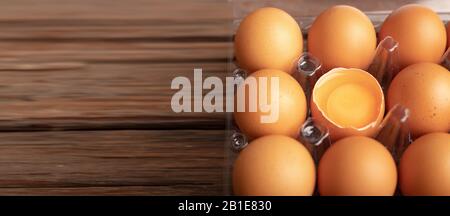 Œufs de poulet et de jaune avec brisés dans une boîte en plastique sur la table en bois. Sélectionnez la profondeur de champ faible focale et l'arrière-plan flou. Banque D'Images