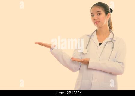 Studio shot of young Asian woman doctor showing quelque chose Banque D'Images