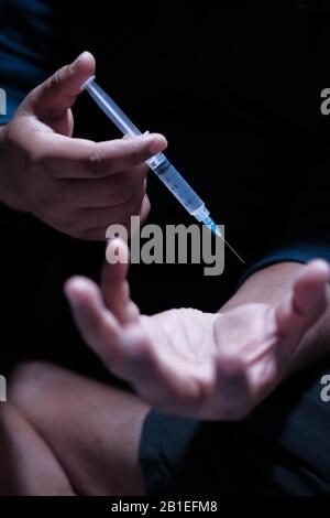 Seringue de maintien de la main de l'homme, concept de toxicomanie Banque D'Images
