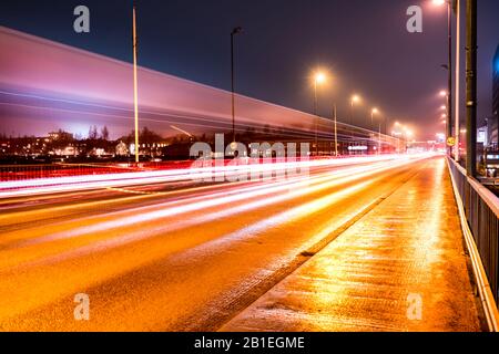 Des traces lumineuses colorées provenant de la circulation nocturne animée sur le pont central de la ville d'Umea, un temps d'automne brumeux, dans le nord de la Suède Banque D'Images