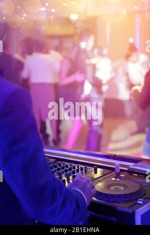 DJ joue de la musique à partir de CD et dansant les gens en arrière-plan pendant l'événement de fête ou la célébration de mariage Banque D'Images