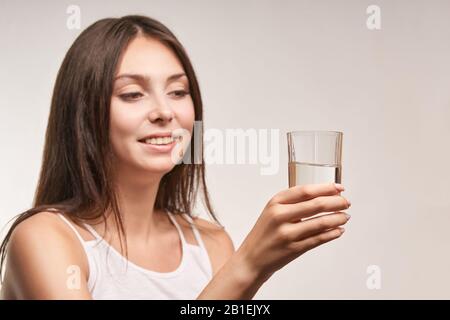 Une jeune fille magnifique tient un verre d'eau. Hydrate visage femelle. Bonne routine pour les femmes.
