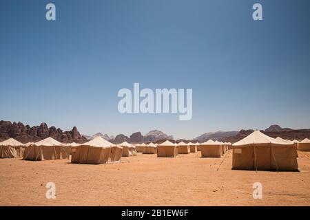 Des rangées infinies de tentes blanches dans le désert, entourées de montagnes rocheuses, dans Le camp de Jabal Rum à Wadi Rum, Jordanie. Banque D'Images