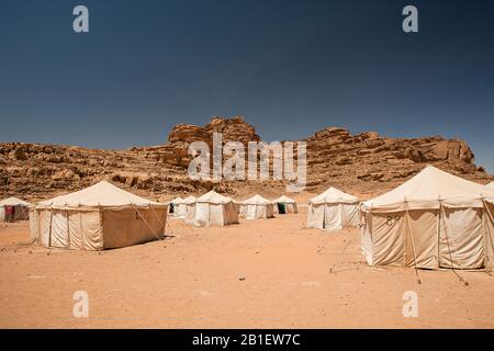 Rangées de tentes blanches dans le désert sous des collines rocheuses dans le camp de Jabal Rum à Wadi Rum, Jordanie. Banque D'Images