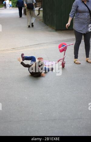 Accident de rue - une fille d'enfant est tombée du scooter d'enfant rose Banque D'Images