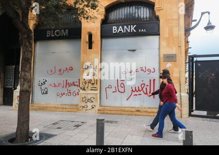 Beyrouth, Liban. 25 Février 2020 : Les piétons traversent une banque à bord endommagée par les manifestants anti-gouvernementaux du quartier central des affaires de Beyrouth qui militent contre la corruption du gouvernement et la crise économique au Liban.Les Manifestants se sont affrontés avec les forces de sécurité libanaises à Beyrouth pour tenter de mettre fin à un vote de confiance au parlement sur le nouveau cabinet qu'ils disent Ne répond pas à leurs exigences, et ne peut pas sauver le Liban de la catastrophe économique.crédit: Amer ghazzal/Alay Live News Banque D'Images