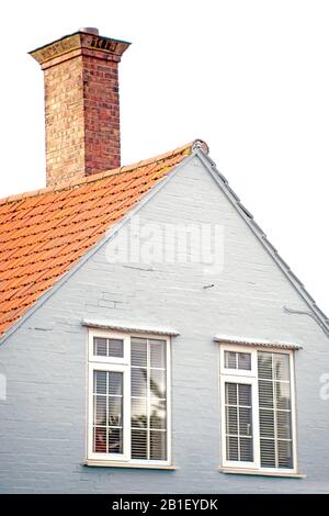 Petite maison de séjour avec cheminée, mur peint en brique et nouvelles fenêtres en plastique. Toit en tuiles. Banque D'Images