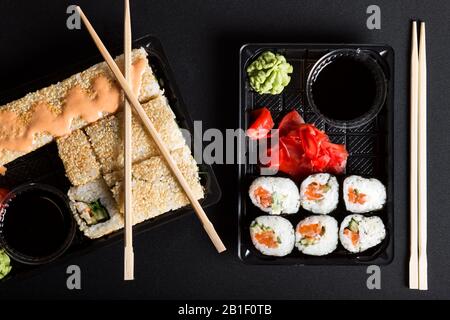 Différents types de sushis dans les boîtes. Des jeux de sushi sur fond noir. Banque D'Images