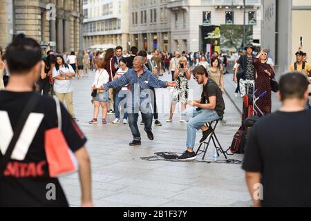 Danser dans la rue comme personne ne regarde, dans une foule de personnes regardant et un bustier jouant de la musique, dans la ville de Piazza del Duomo Milan Banque D'Images