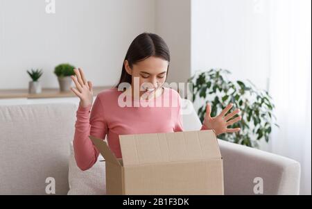 Une femme surjoée millénaires ouvrant une boîte en carton à la maison Banque D'Images