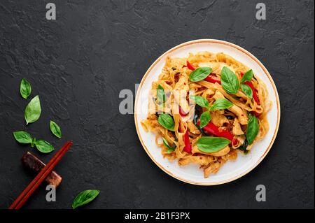 Nouilles thaï Drunken ou Pad Kee Mao en plaque blanche sur fond d'ardoise noir. Les Nouilles dunken sont un plat de cuisine thaïlandaise avec Des Nouilles de riz, de la viande de poulet, du Ba Banque D'Images