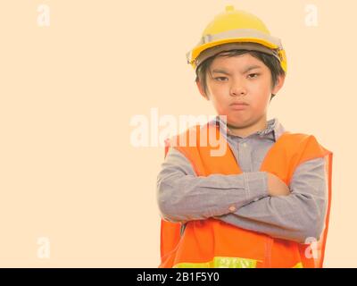 Studio shot of angry boy japonais construction worker with arms crossed Banque D'Images