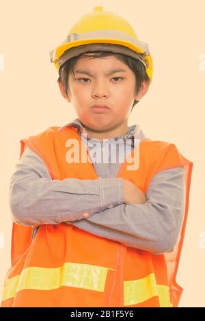 Studio shot of angry boy japonais construction worker with arms crossed Banque D'Images