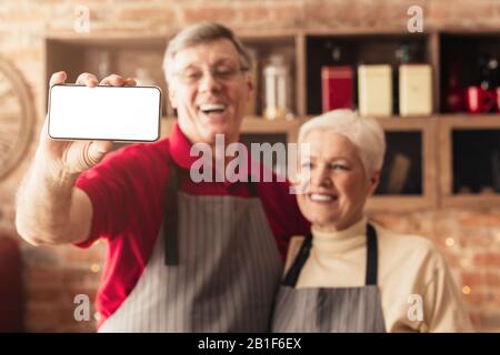 Heureux couple senior prenant selfie sur smartphone moderne avec écran blanc Banque D'Images