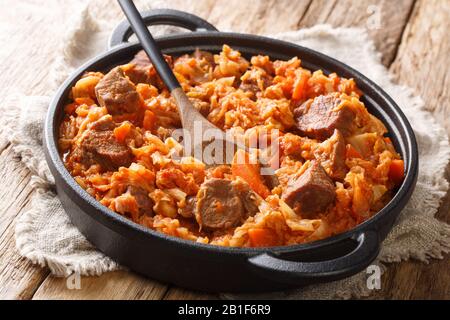 Le chou est savoureux avec de la viande, des tomates, des carottes et des oignons dans une poêle sur la table. Horizontale Banque D'Images