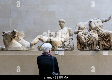 Un visiteur regarde les marbres du Parthénon, statues du Pediment oriental, également connues sous le nom de marbres d'Elgin au British Museum, Parthénon Gallery, Londres, Angl Banque D'Images