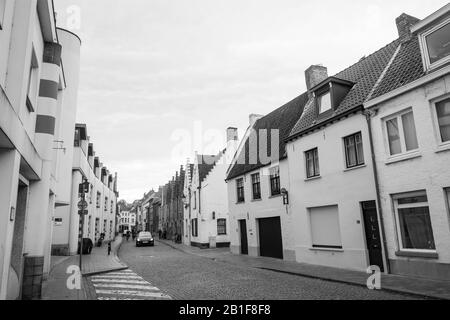 Même en dehors de son centre médiéval bondé, Bruges offre de charmantes rues, ici avec de jolies maisons blanches. Une voiture vous conduit dans la rue pavée. Banque D'Images